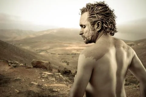 Warrior man covered in mud on desert background Stock Photos