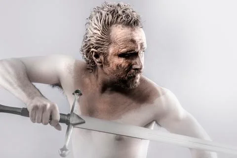 Warrior man covered in mud with sword Stock Photos