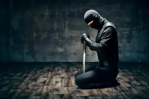 Warrior man sitting on floor posing with a sword Stock Photos