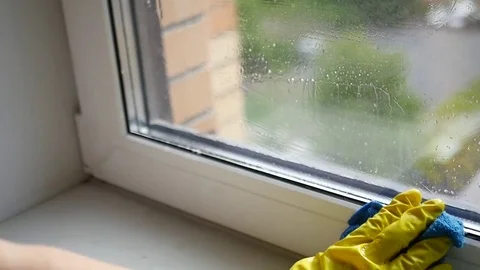 Wash the dirty window with a scraper in a yellow rubber glove. SLOW MOTION. HD Stock Footage 77575678