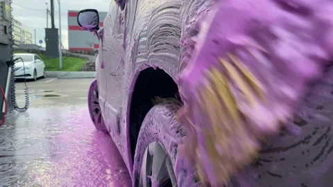 Wash dry dirt off surface soap brush rubs headlight of car at car wash. Active Stock Footage 238776624