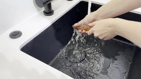 Wash vegetable process. Hand cleaning fresh carrot under faucet water on co.. Stock Footage 320476599
