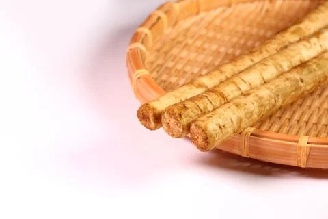 Washed burdock root on a bamboo colander Stock Photos