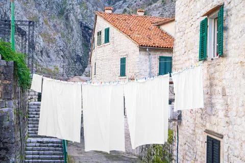 Washed clean white sheets, tablecloths and bed linen are dried on rope above Stock Photos