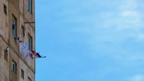 Washed clothes are hung to dry on ropes stretched between two fasteners on Stock Footage 236584629