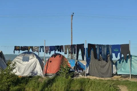 Washed clothes drying on barbed wire of camp fence Stock Photos
