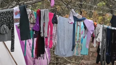 Washed laundry hangs on a rope and is dried. freshly washed pants and shirts Stock Footage 229893512