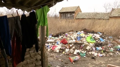 Washed old laundry dries on wire and a pile of garbage in the yard Stock Footage 124595003