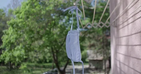Washed textile mask drying in the sun covid 19 pandemic crisis Stock Footage 128747190