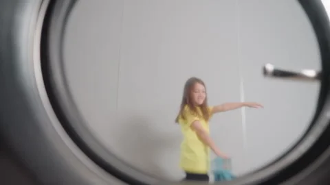 Washer Door Reflection Shows Kid Dancing Past With Round Handle Visible Vidéo 318840505