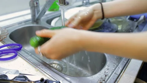 Washes cucumbers in the kitchen sink Stock Footage 206823878