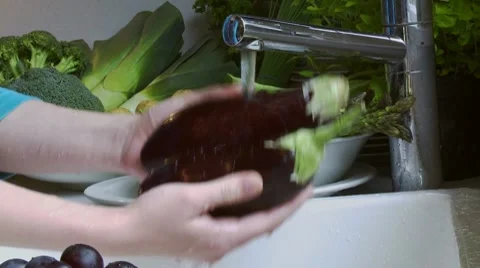 Washing aubergines under running water Stock Footage