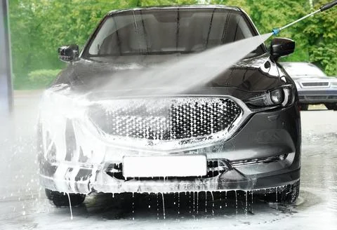 Washing auto with high pressure water jet at outdoor car wash Stock Photos