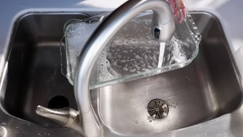 Washing baking dish in kitchen sink slow motion Stockbeeldmateriaal 289932644