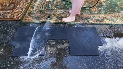 Washing a car mat with a high-pressure cleaner in the yard Stock Footage 247437557