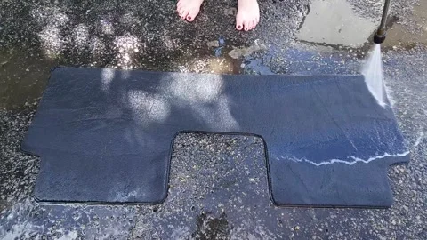 Washing a car mat with a high-pressure cleaner in the yard Stock Footage 247437574