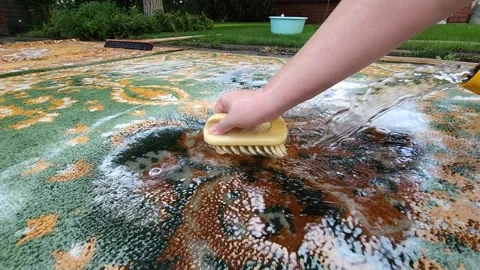 Washing carpets with a brush with detergents in the yard Stock Footage 247437576