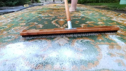 Washing carpets with a brush with detergents in the yard Stock Footage 247437583