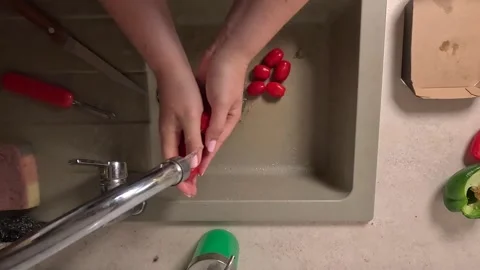 Washing cherry tomatoes under running tap water in kitchen sink. Overhead view Stock Footage 316472209
