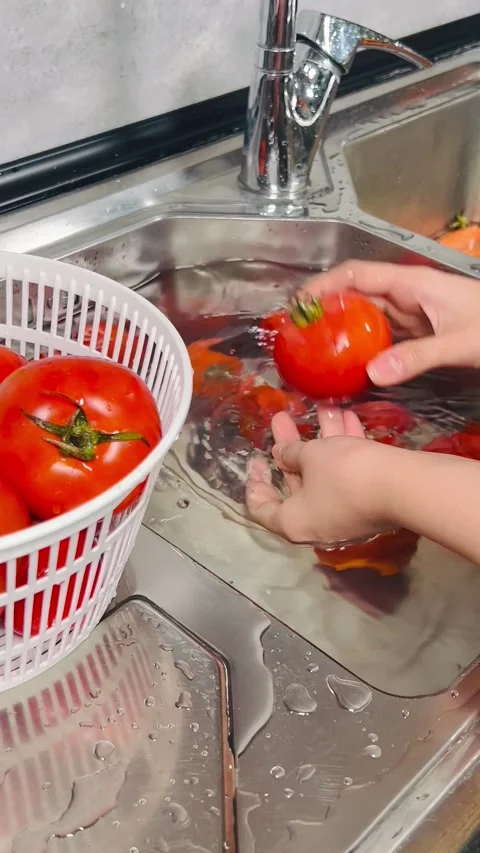 Washing fresh red tomatoes in kitchen sink and placing in colander Stock Footage 338157464