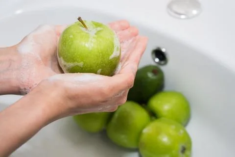 Washing fruit. Hands and soapy green apple Stock Photos