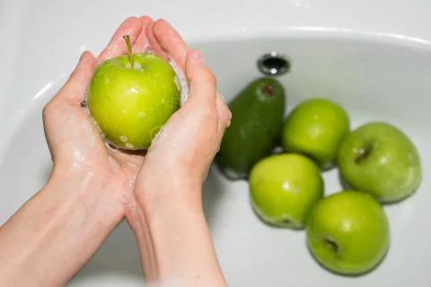 Washing fruit. Hands and soapy green apple Stock Photos