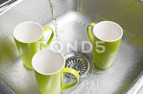 Washing green cups in the kitchen sink Stock Photos