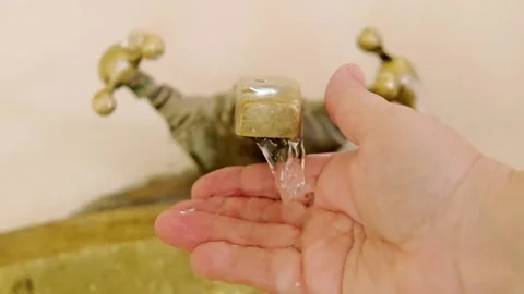 Washing hands in Rustic brass sink, morning skincare routine in Moroccan-st.. Stockbeeldmateriaal 346784887
