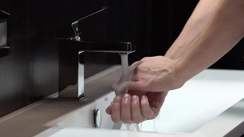 Washing hands under a chrome tap chrome on a dark background, slow motion Video stock 75682555