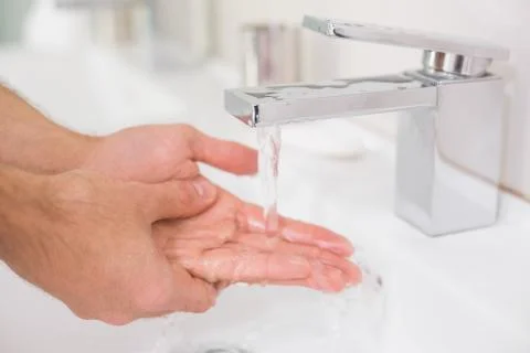 Washing hands under running water at bathroom sink Stock Photos
