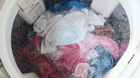 Washing machine agitating colorful clothes with soapy water and bubbles, Stock Footage 335643738