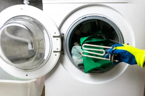 Washing machine breakdown. The master retrieves the floor part. In the hands  Stock Photos
