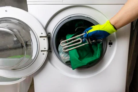 Washing machine breakdown. The master retrieves the floor part. In the hands  Stock Photos
