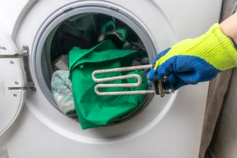 Washing machine breakdown. The master retrieves the floor part. In the hands  Stock Photos