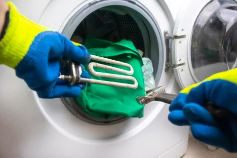 Washing machine breakdown. The master retrieves the floor part. In the hands  Stock Photos
