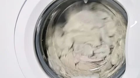 Washing machine with clothes spinning inside in a home laundry Stock Photos