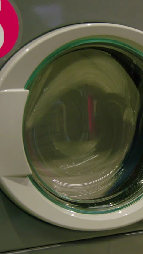 Washing machine door shows water swirling inside as laundry spins, highlighting Видео 330282900