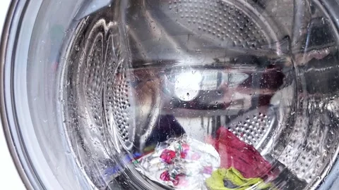Washing machine drum in action with clothes and water Stock Footage 315089348