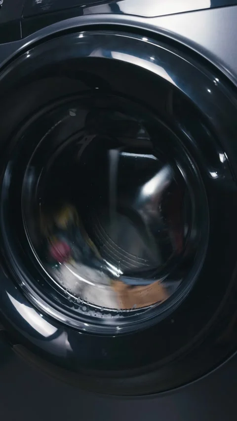 Washing machine drum rotating, cleaning clothes with water and suds during a Stock Footage 344911514