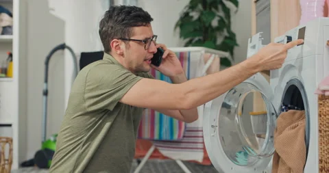 Washing machine failure. Upset man calls service compur phone calls plumber to Stock Footage 200849606