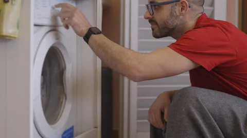 Washing machine in the laundry. Man loading the device Stock Footage 152038618