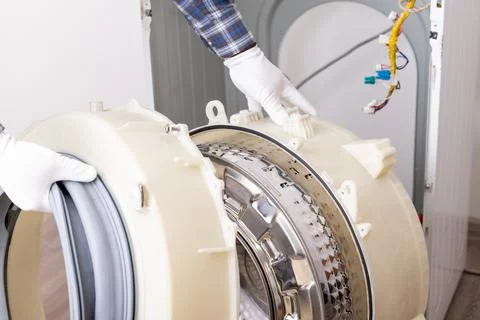 Washing machine repair process with technician handling parts indoors Stock Photos