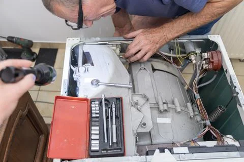 Washing machine repair technician using tools from the organizer Stock Photos