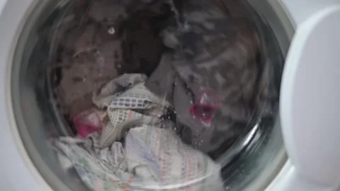 A washing machine shows various laundry items being washed, including fabrics of 스톡 동영상 337101456