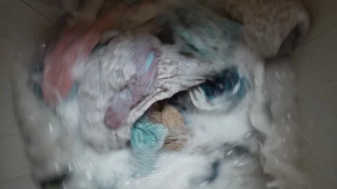 Washing machine spinning clothes in water mixed with detergent Stock Footage 256285070