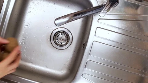 Washing potatoes with your hands in the kitchen sink Stock Footage 129467338