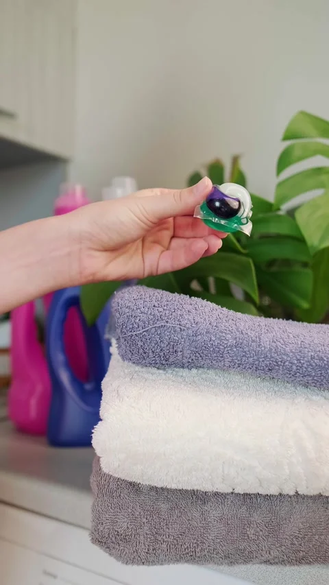 Washing powder bottles, a stack of towels on the washing machine, and a washing Stock Footage 295286125