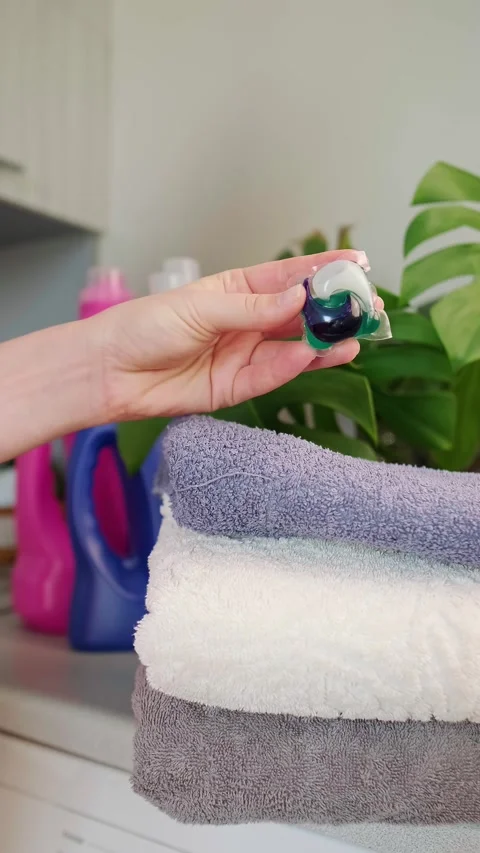 Washing powder bottles, a stack of towels on the washing machine, and a washing Stock Footage 295286152