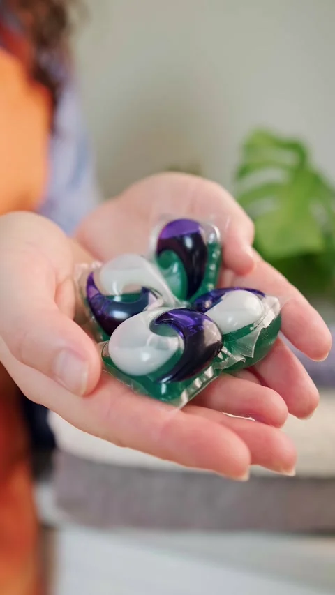 Washing powder bottles, a stack of towels on the washing machine, and a washing Stock Footage 295286184
