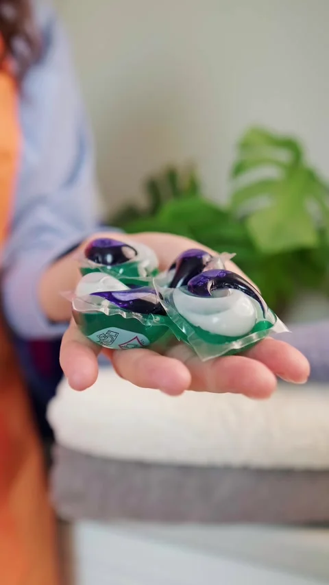 Washing powder bottles, a stack of towels on the washing machine, and a washing Stock Footage 295286207